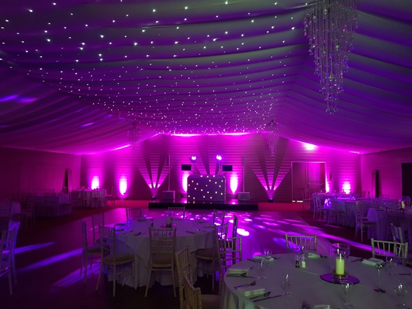Professional DJ equipment setup with lighting and a full dance floor at a party